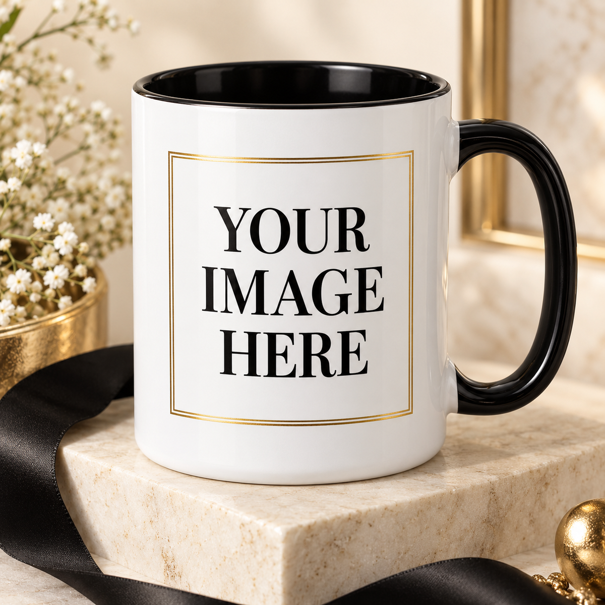 A white ceramic mug with a black interior and black handle, featuring a gold-bordered placeholder box with the text 'YOUR IMAGE HERE' on the front. The mug is styled on a light marble block with a black ribbon, baby's breath flowers, and gold decorative accents.